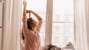 A woman waking up in her room to a bright and sunny morning
